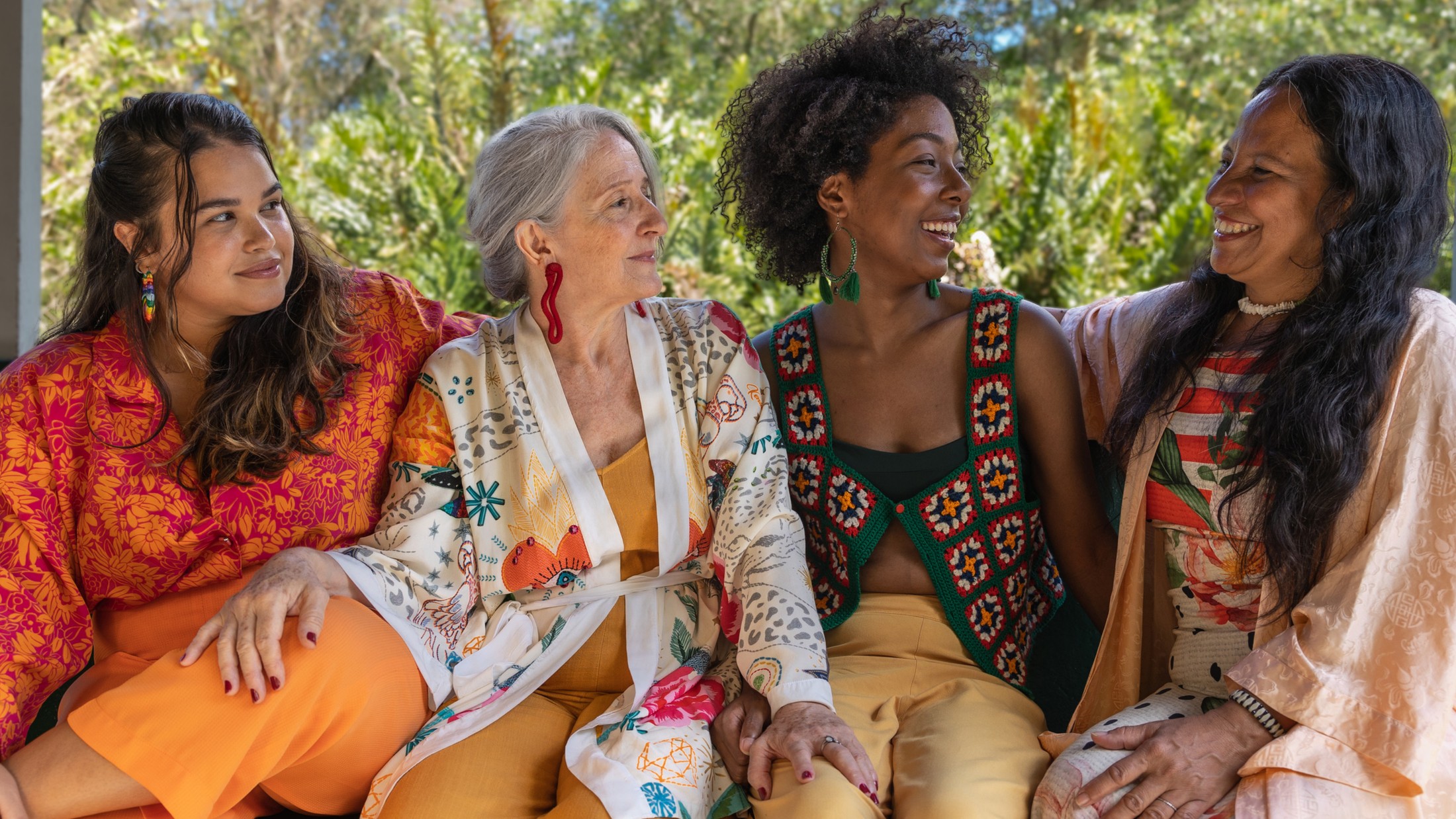 Four women of different ages and backgrounds sitting together outdoors